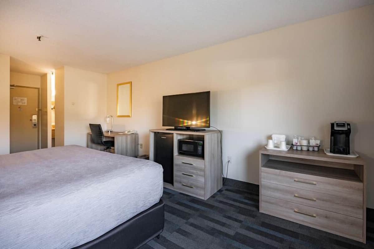 A hotel room with a large bed, a desk with a computer, a microwave, and a coffee maker.
