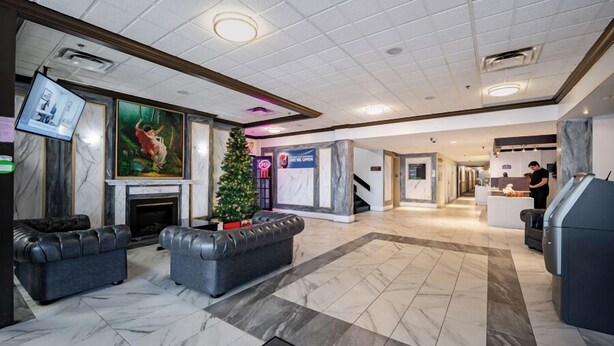 A hotel lobby with a fireplace, two sofas, a Christmas tree, and a reception desk. - HFX Airport Hotel (Goffs)