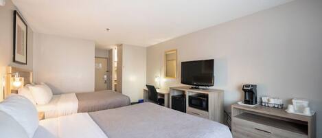 A hotel room with two beds, a desk, a television, a coffee maker, and a microwave.