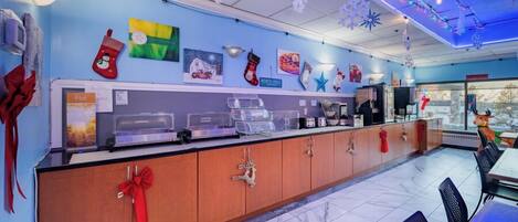 A restaurant with a long counter, festive decorations, and a view of the city.
