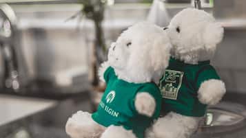 Two white teddy bears wearing green shirts with logos, sitting on a surface.