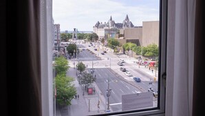 Paisatge urbà visible per una finestra, amb una vista del centre de la ciutat, incloent edificis i un carrer.