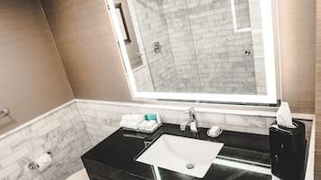Un baño moderno con un lavabo negro, inodoro blanco y un espejo grande sobre el lavabo.