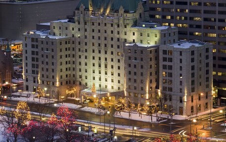 A multi-story hotel with a classic architectural style, featuring a prominent entrance and a large parking area.
