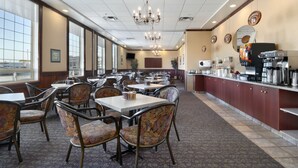 A spacious dining area with multiple tables and chairs, a bar area with coffee machines, and large windows providing natural light. - Ramada by Wyndham Red Deer Hotel and Suites (Red Deer)