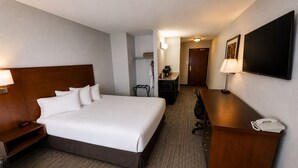Ein Hotelzimmer mit einem gro ßen Bett, einem Schreibtisch mit Telefon, einem Fernseher und einer Mikrowelle.
