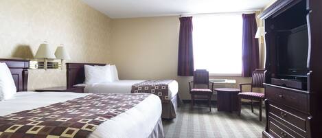 A hotel room with two beds, a desk, a chair, a TV, and a window with curtains.
