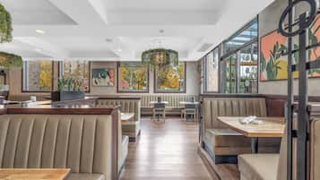 A restaurant with booth seating, wooden tables, and large windows with autumn foliage views.