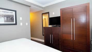 Quarto de hotel com uma cama, um guarda-roupa, uma televisão e um quadro na parede.