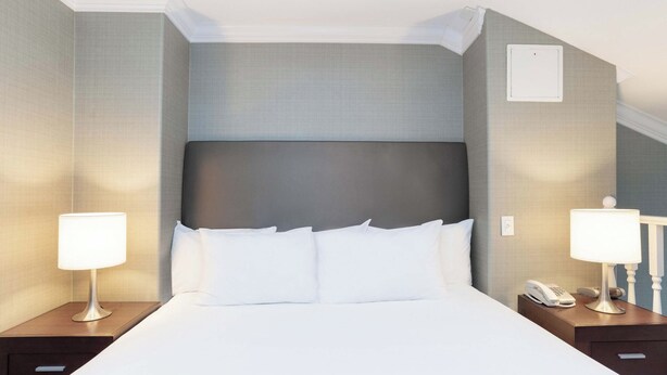 Een hotelkamer met een groot bed, twee nachtkastjes, een telefoon en een wandlamp.