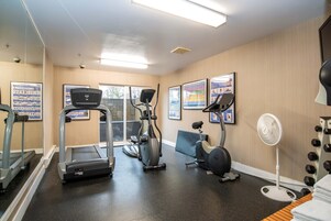 Un gimnasio con cintas de correr, elípticas y una bicicleta estática.