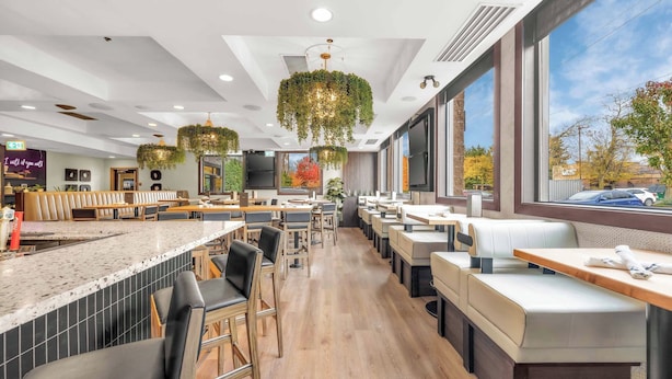 Un restaurant moderne doté d’un long comptoir, de plusieurs espaces de restauration et de grandes fenêtres donnant sur l’extérieur.