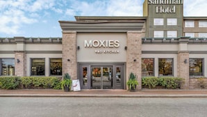 Un bâtiment sur lequel on peut lire une enseigne « MOXIES R&D Kitchen » et, au-dessus, une autre enseigne « Sandman Hotel ».