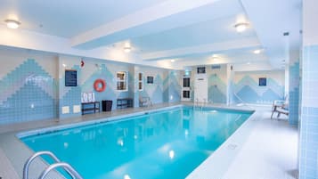 A large indoor swimming pool with clear blue water, tiled walls, and a tiled floor.