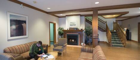 A spacious living room with a fireplace, wooden floors, and a staircase leading to an upper level.