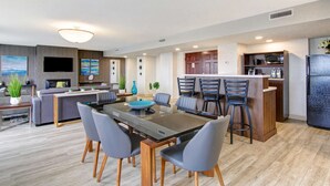 A modern open-plan living area with a dining table, chairs, a sofa, and a kitchen area with a microwave and refrigerator. - The Park Hotel London (London)