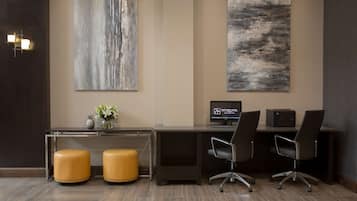 Un moderno área de recepción de hotel con un mostrador, dos sillas de oficina, una computadora y dos otomanas de cuero.