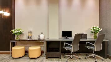 A modern office space with a desk, two chairs, a computer, and decorative items.