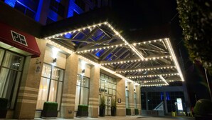 A hotel entrance with a covered outdoor area, large windows, and a sign indicating a parking area. - The Park Hotel London (London)