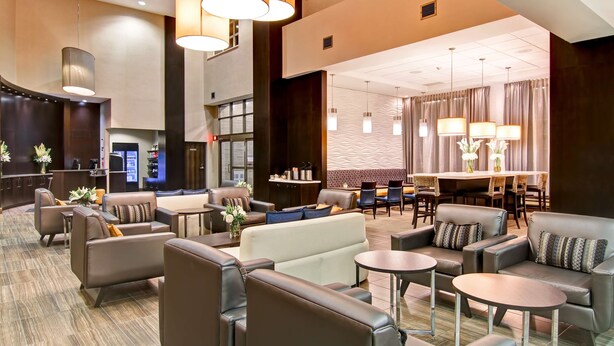 A modern hotel lobby with leather seating, a reception area, and a dining space. - The Park Hotel London (London)