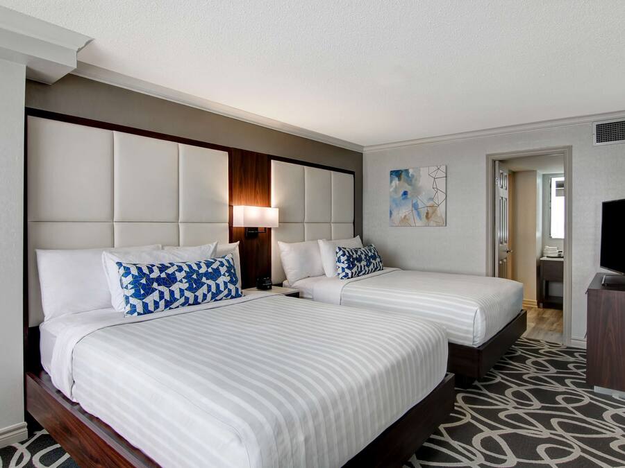 A hotel room with two beds, a TV, and a painting on the wall.