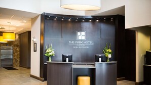 A reception desk at The Park Hotel London with a modern design, a logo, and a reception area. - The Park Hotel London (London)