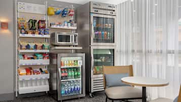 Habitación de hotel con minibar, microondas, refrigerador y zona de estar con mesa y sillas.