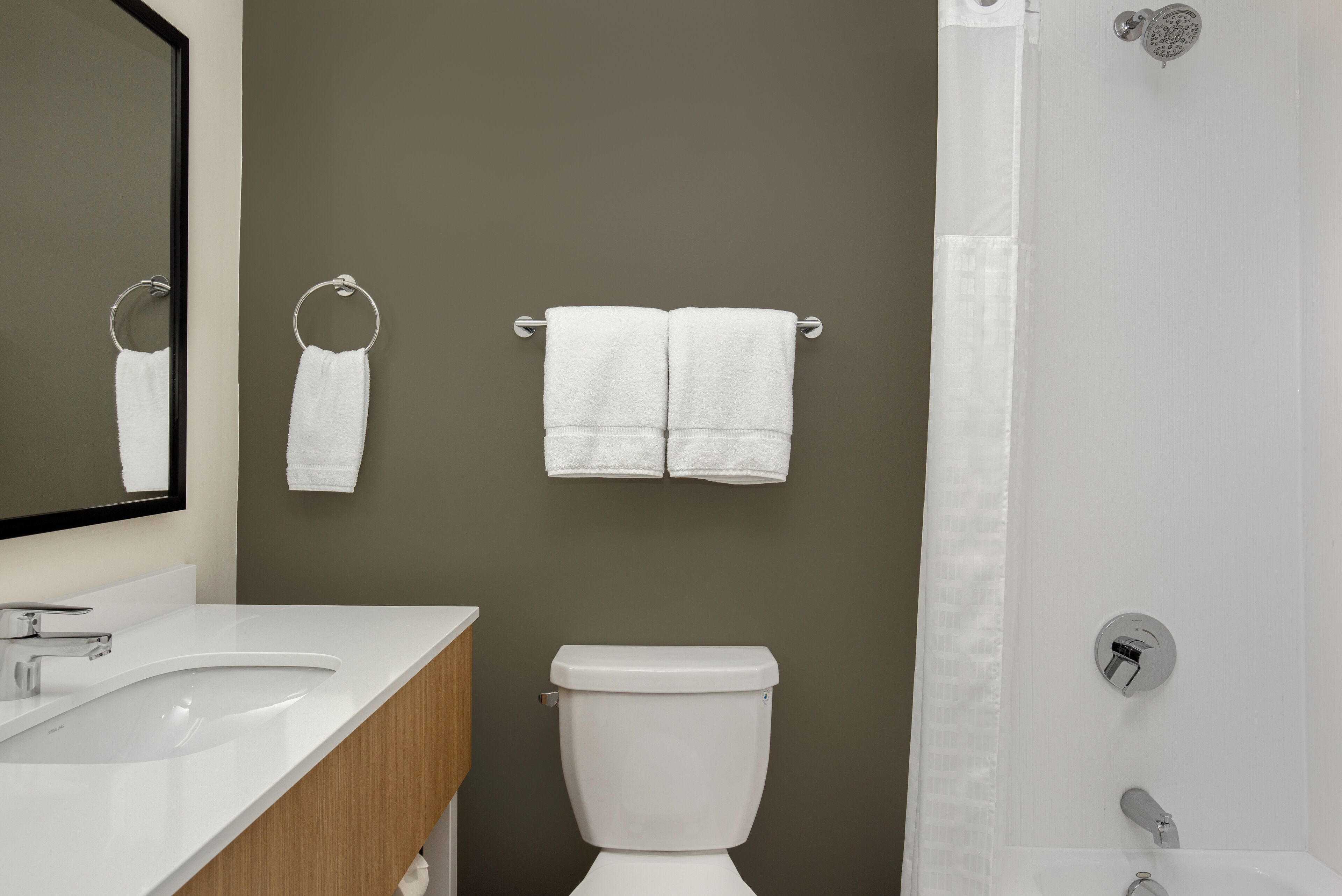 A bathroom with a white sink, a toilet, and two towels hanging on the wall.