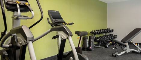 Un gimnasio con cintas de correr, mancuernas y equipo de ejercicio.