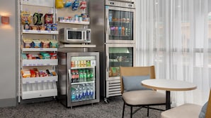 A kitchenette with a microwave, refrigerator, and beverage dispenser, a chair, and a table. - Spark by Hilton Toronto Airport (Toronto)