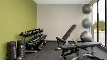Un gimnasio con banco, mancuernas y pelotas de ejercicio.