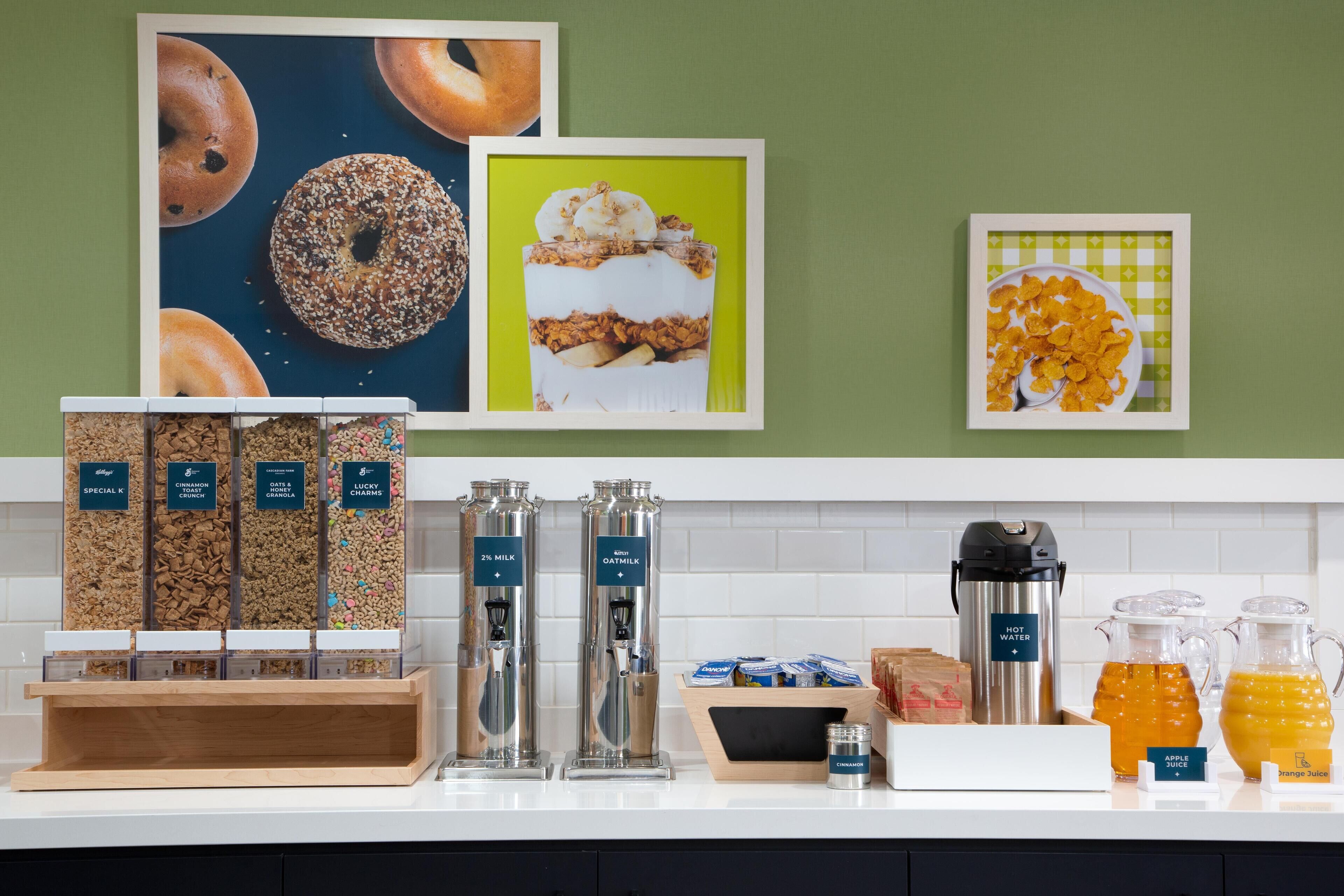 A breakfast bar with various food and drink options, including cereal, granola, and juices.