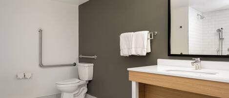 Un baño moderno con inodoro blanco, lavabo con encimera de madera y espejo.