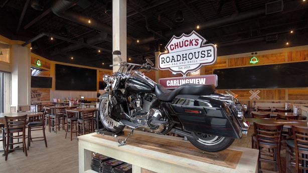 A restaurant interior with a motorcycle on display, wooden tables, and chairs. - Spark by Hilton Toronto Airport (Toronto)