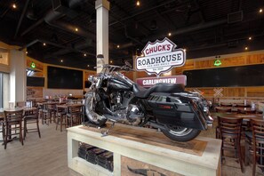 Een restaurantinterieur met een tentoongestelde motor, houten tafels en stoelen.
