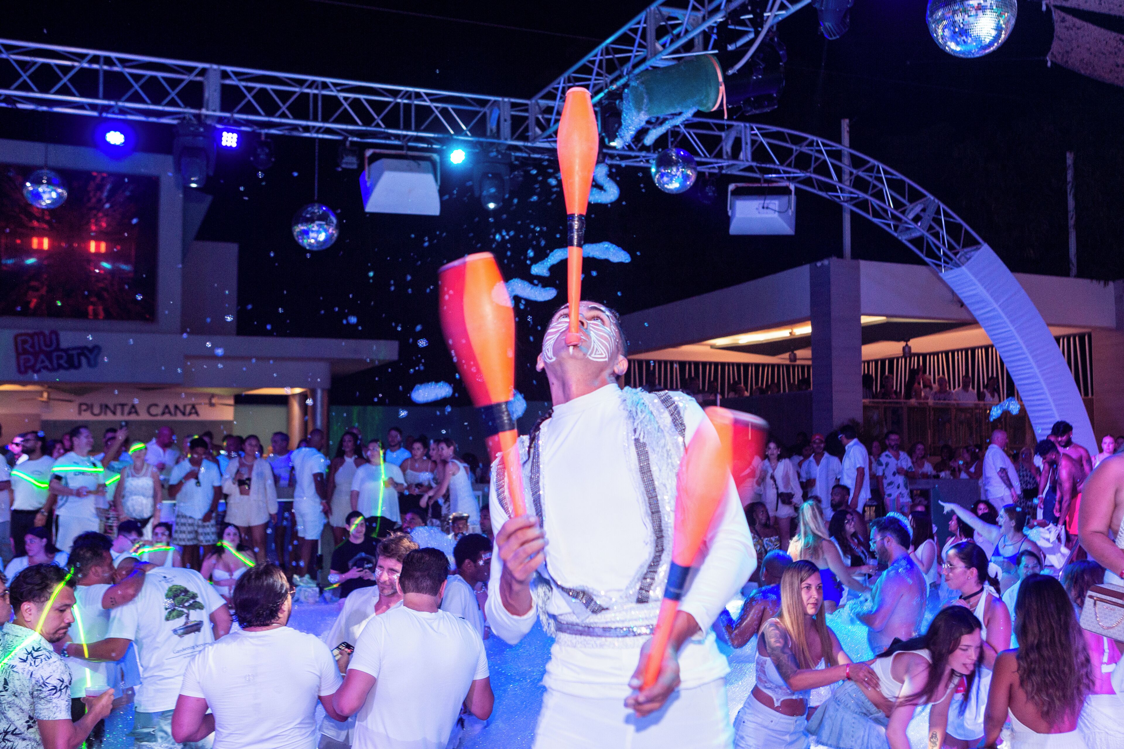 A crowded indoor event with a performer juggling clubs, surrounded by an audience.