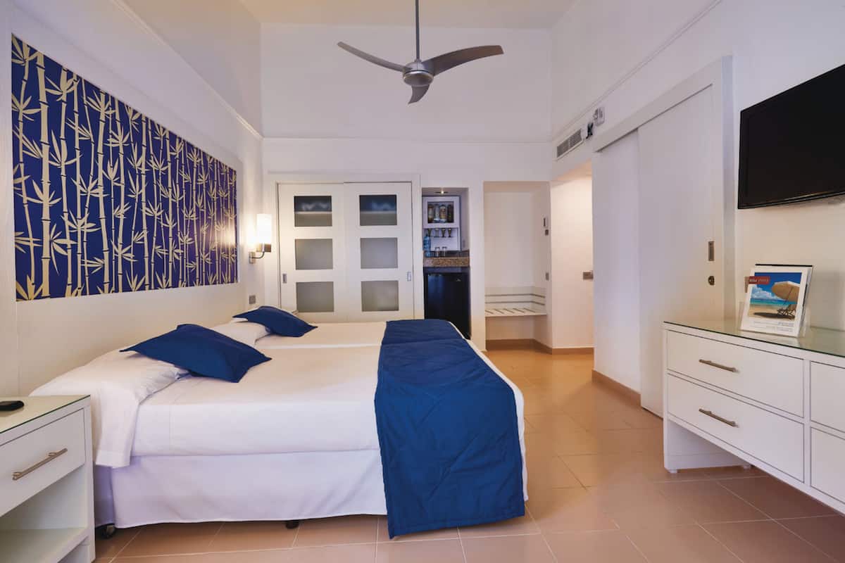 A hotel room with a bed, a desk, a TV, and a wardrobe.