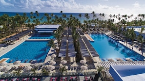 A resort with multiple swimming pools, sun loungers, and palm trees.