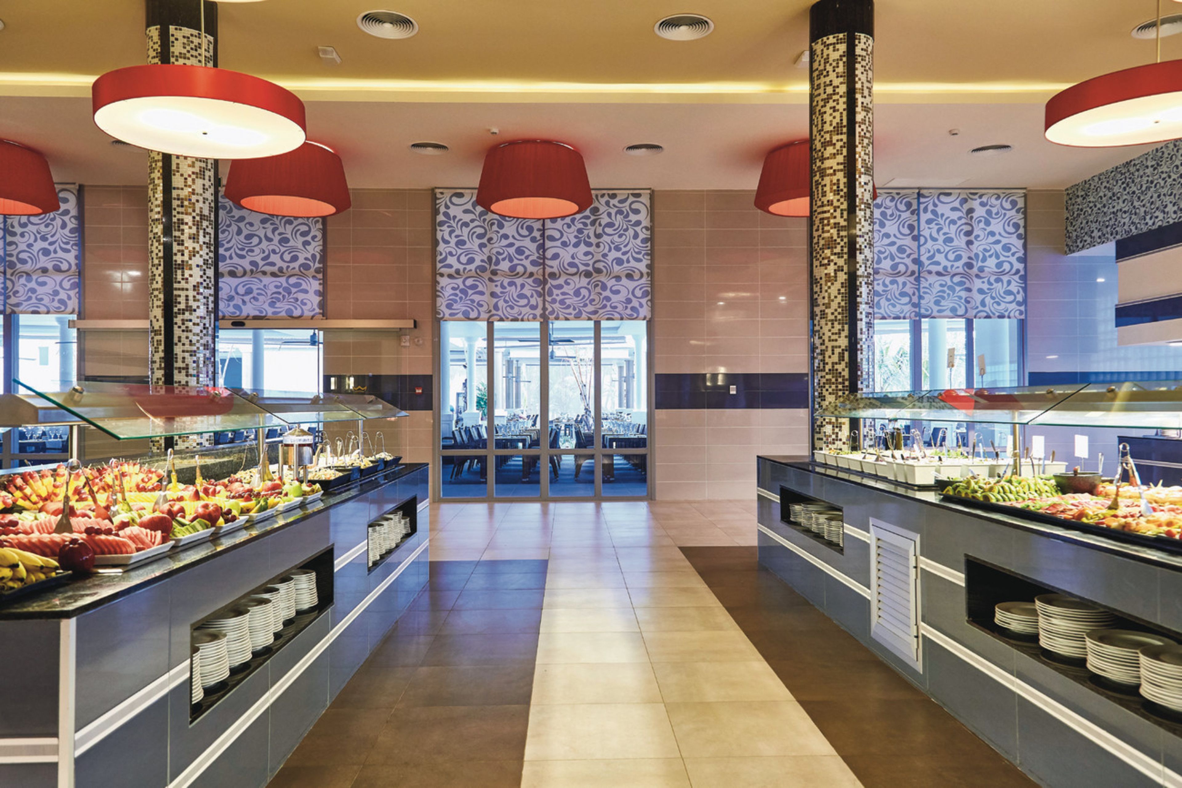 A buffet area with multiple food stations, a central seating area, and patterned wall tiles.