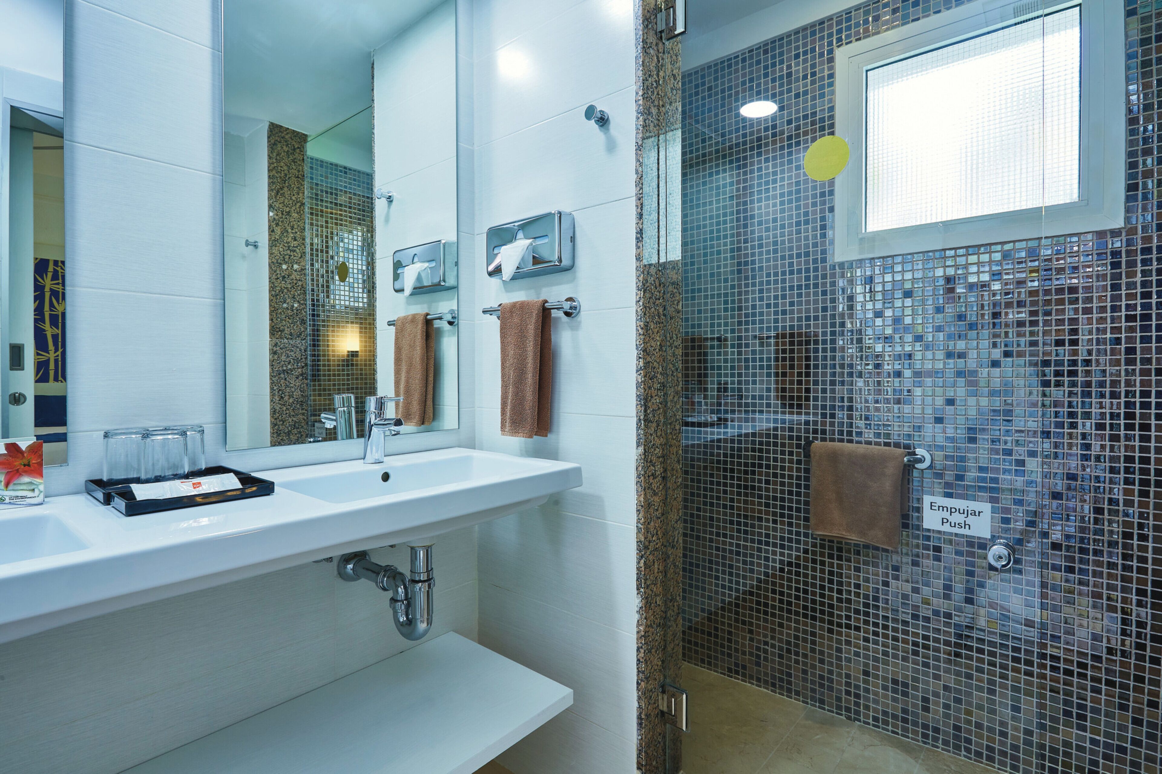 Un baño moderno con lavamanos blanco, espejo y cabina de ducha de vidrio.