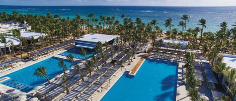 A resort with multiple swimming pools, sun loungers, and palm trees.