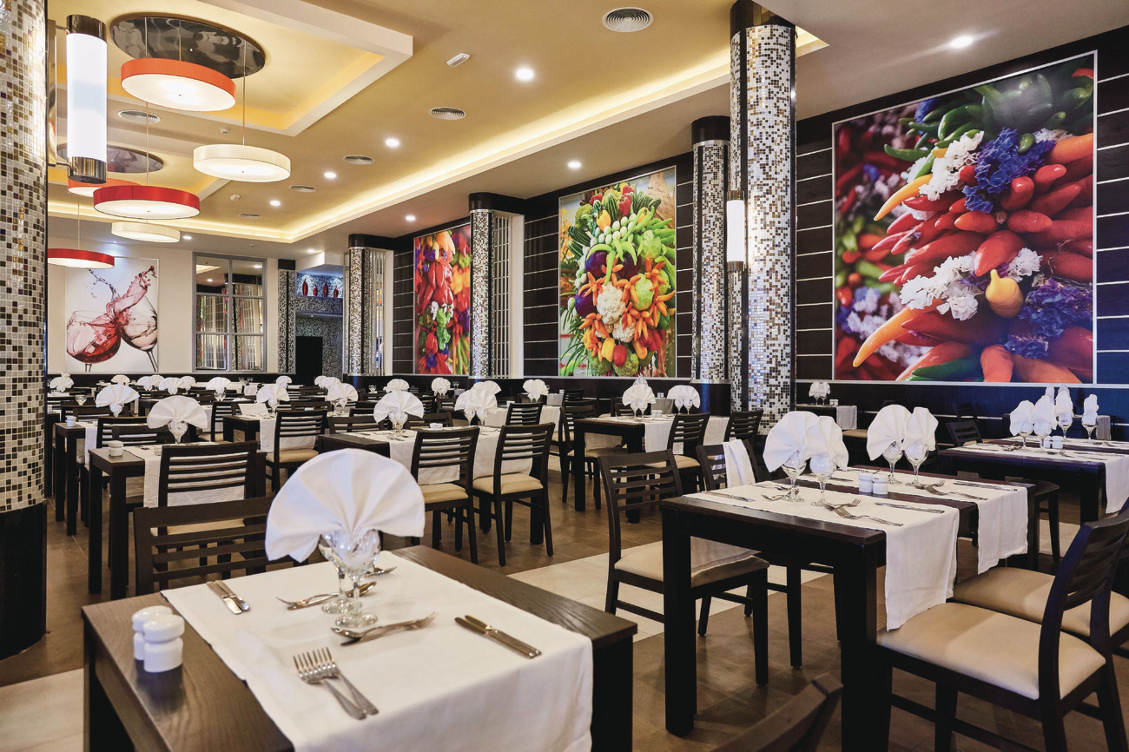 A restaurant with multiple tables set for dining, featuring white tablecloths and neatly arranged cutlery.