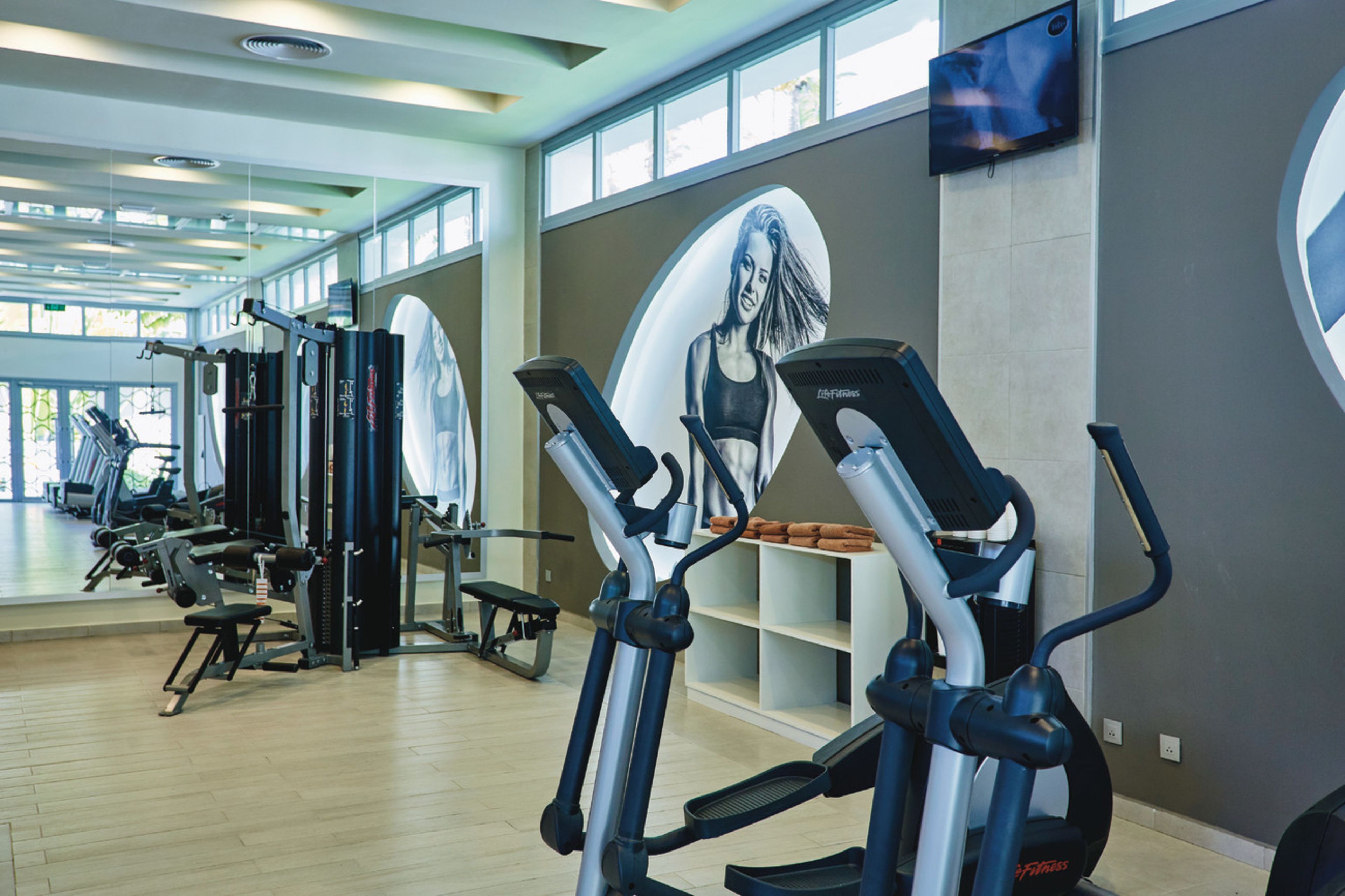 A gym with cardio machines, weightlifting equipment, and a large mirror.