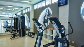 A gym with cardio machines, weightlifting equipment, and a large mirror.