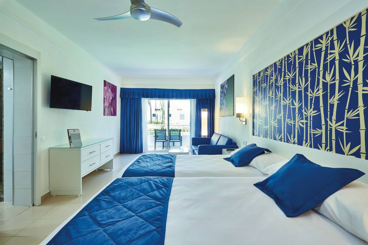 A hotel room with a bed, a desk, a TV, and a view of the outside.