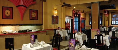 A restaurant with multiple tables, ceiling fans, and traditional Asian decor.
