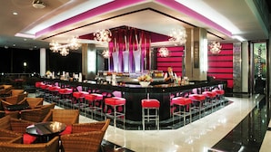 A bar area with a counter, stools, and a bartender.