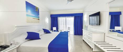 A hotel room with a large bed, a TV, a desk, and a window with curtains.