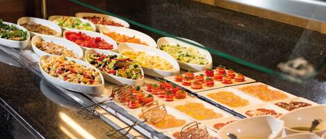 A buffet with various dishes including salads, pasta, and appetizers.