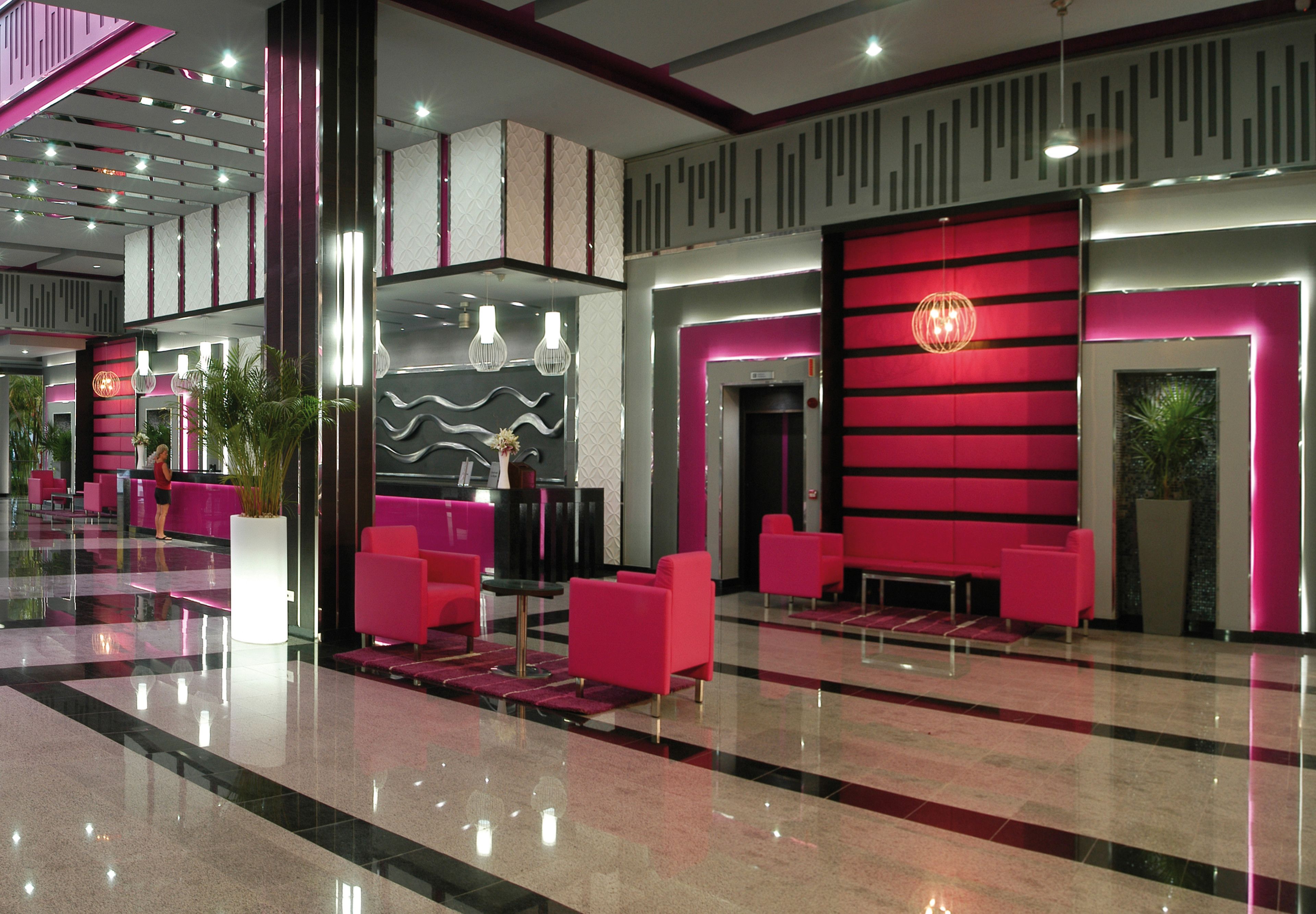 A modern lobby with reflective floors, red and white decor, and seating areas.